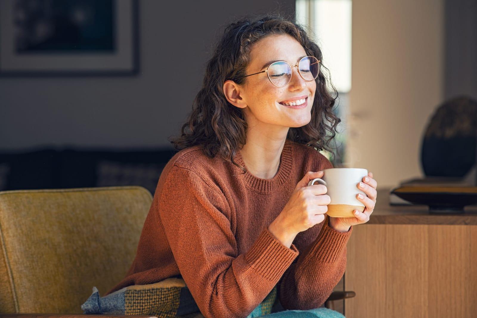 Kvinna njuter av en kopp kaffe i fåtöljen